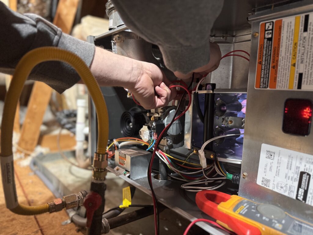 Atlas technician testing electrical connections inside a gas furnace