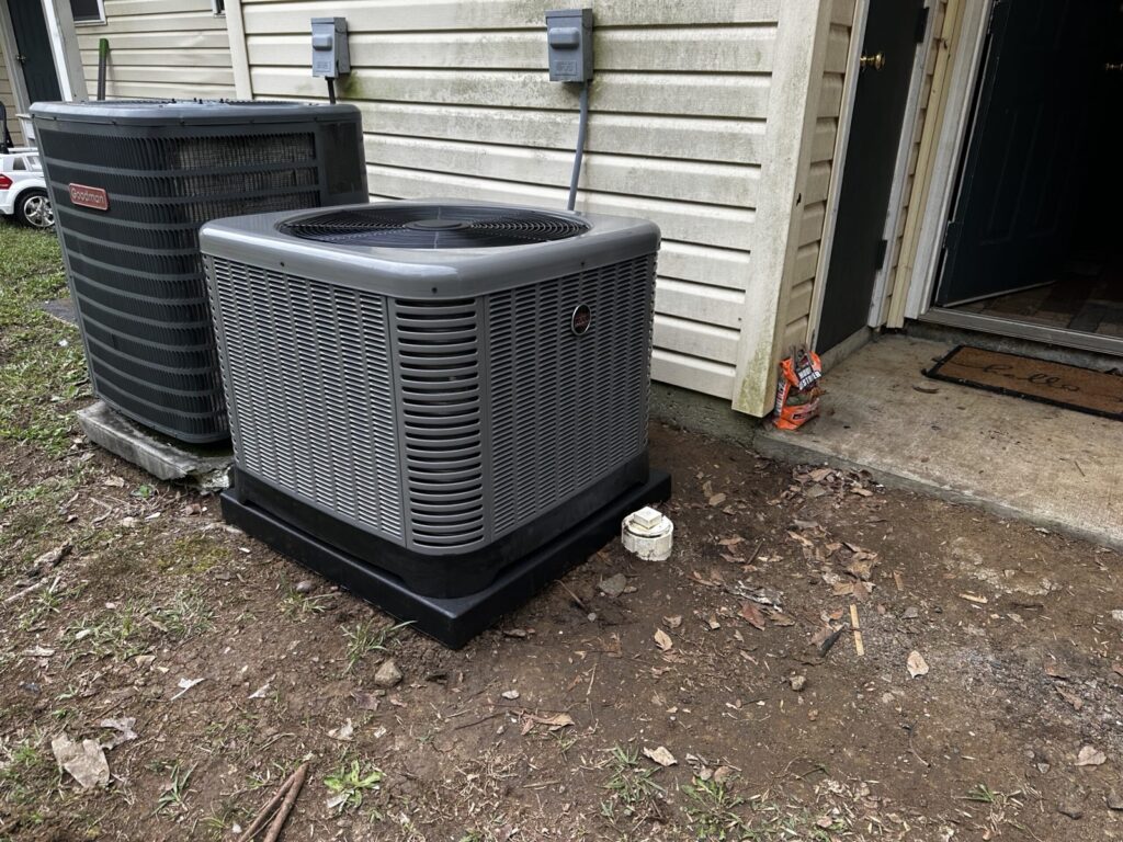 New Rheem outdoor HVAC unit installed beside an older Goodman unit at a home